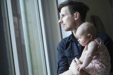 Father looking through window with daughter (2-5 months).