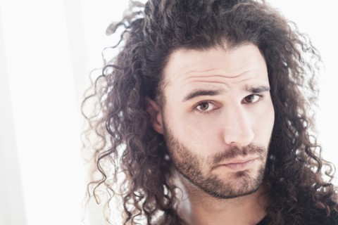 Portrait of young man with long curly hair.