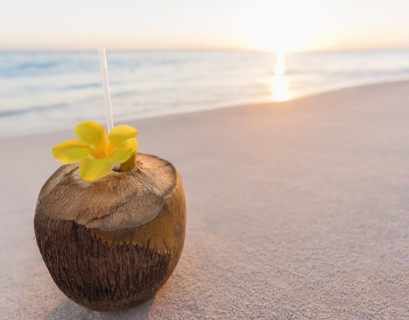 Tropical cocktail in coconut shell on sandy beach