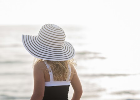 Girl (4-5) in striped sunhat by sea