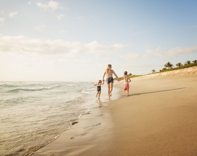 Mother running with boy (6-7) and girl (4-5) on beach by water