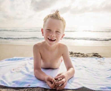 Portrait of boy (6-7) and girl (4-5) lying on beach laughing
