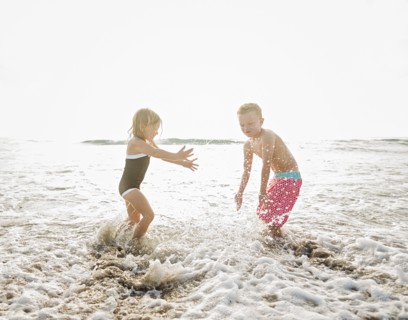 Mother walking with boy (6-7) and girl (4-5) on beach by water