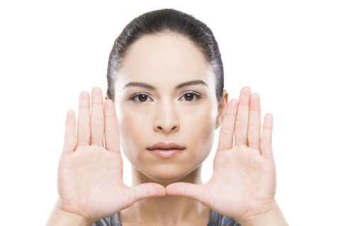 Young woman with hands in front of face