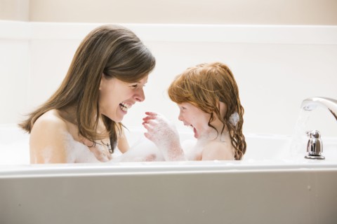 Mother and daughter (4-5) having bubble bath