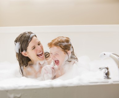 Mother and daughter (4-5) having bubble bath