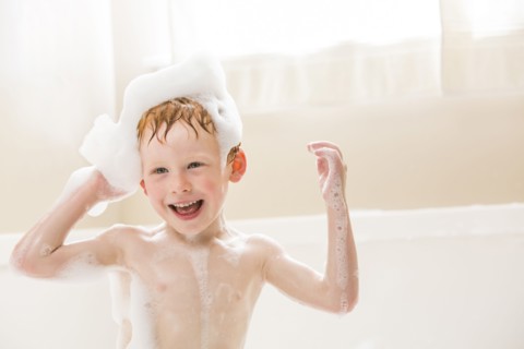 Smiling boy (2-3) having bubble bath