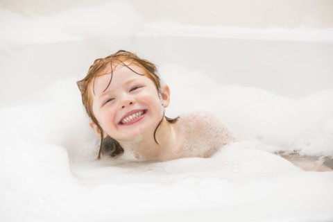 Smiling girl (4-5) having bubble bath
