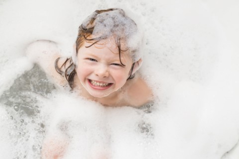 Smiling girl (4-5) having bubble bath