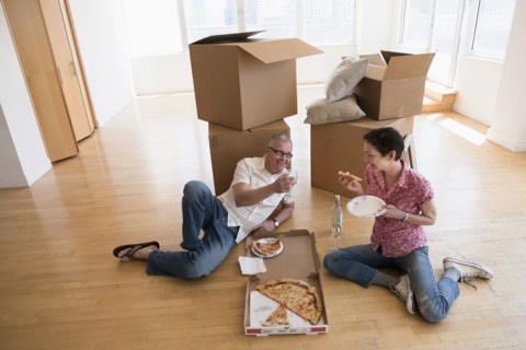 Couple eating pizza in new apartment.