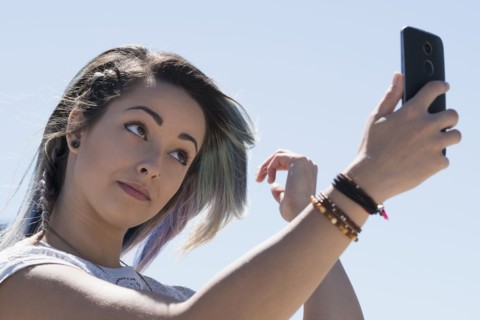 Young woman holding mobile phone.