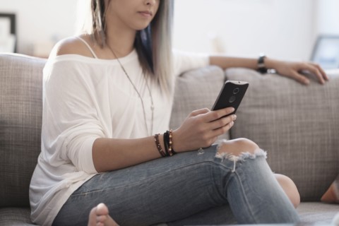 Young woman using mobile phone at home.
