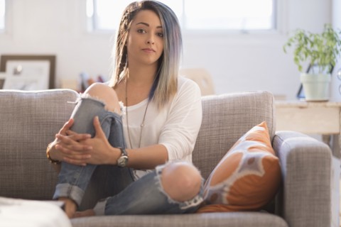 Confident young woman sitting on sofa.