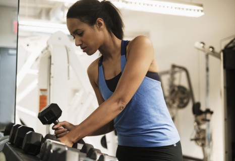 Woman choosing dumbbells for training.