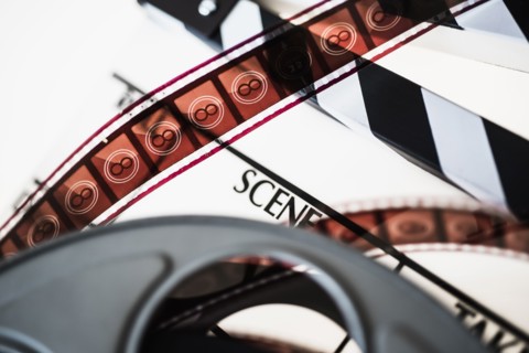 Close-up of film reel and slate against white background.