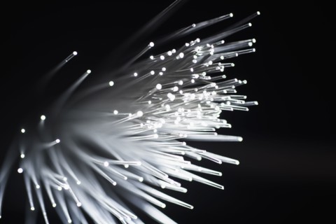 Bunch of glowing fiber optic cables on black background.