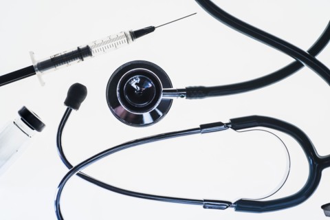 Stethoscope, syringe and test tube on white background.