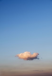 Single cloud on blue sky at sunset.