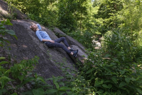 Woman lying on stone in forest.