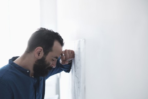 Tired man leaning by wall.