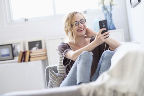 Woman sitting on sofa and using mobile phone.
