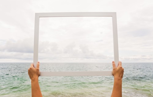 Person holding frame against cloudy sky