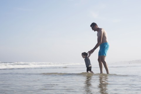 Father with daughter (18-23 months) wading in sea