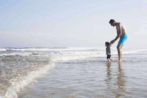 Father with daughter (18-23 months) wading in sea