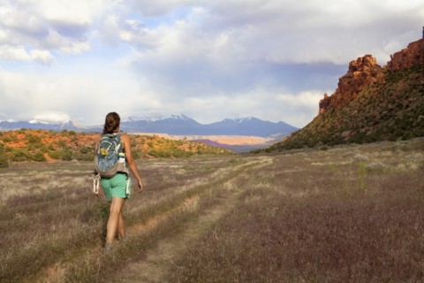 Woman with backpack walking in grass