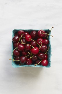Overhead view of cherries in blue fruit carton