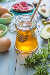 Jar of honey with dipper and fresh herbs