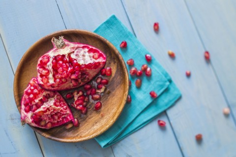 Overhead view of halved pomegranate on wooden plate