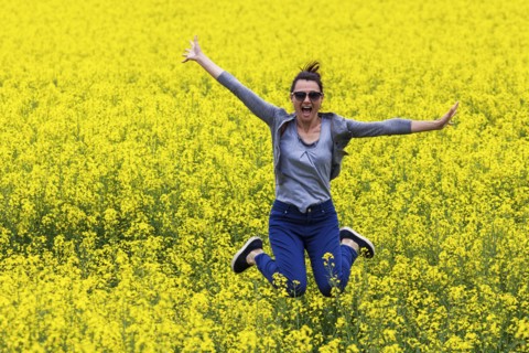 Italy, Tuscany, Woman jumping in canola field
