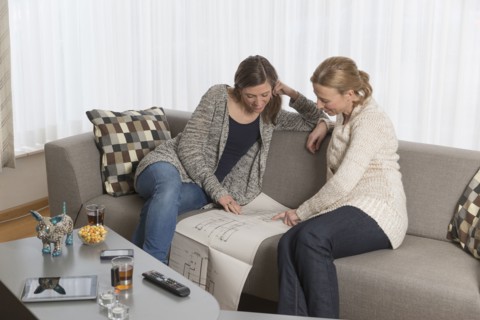 Women sitting on sofa and analyzing blueprint