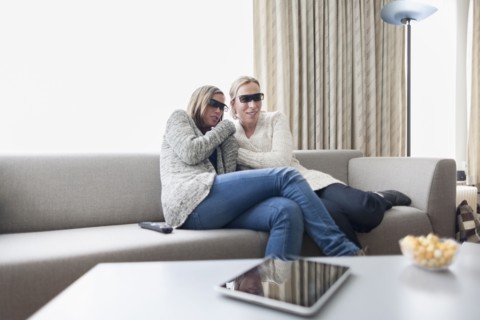 Women in 3d glasses sitting on sofa in living room