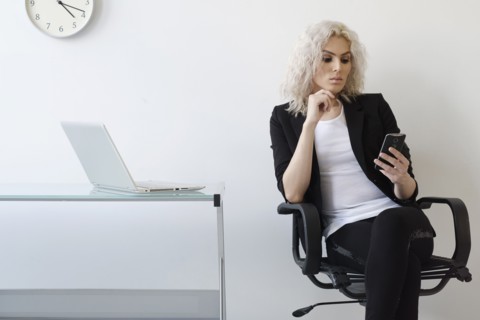 Young businesswoman using phone in office.