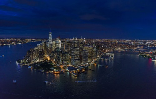 USA, New York, New York City, Manhattan, Aerial view of illuminated skyline with harbor at night.