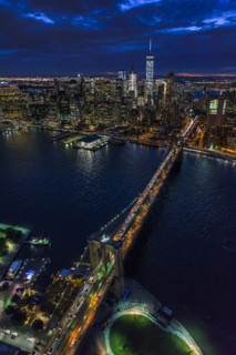 USA, New York, New York City, Manhattan, Aerial view of illuminated skyline with harbor and Brooklyn bridge at night.