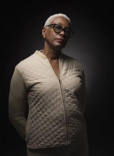 Studio shot of woman standing with hands behind back.