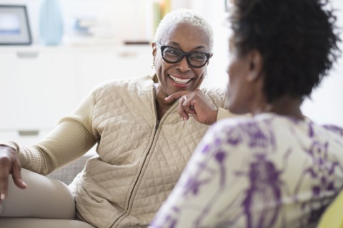 Smiling women sitting and talking in living room.