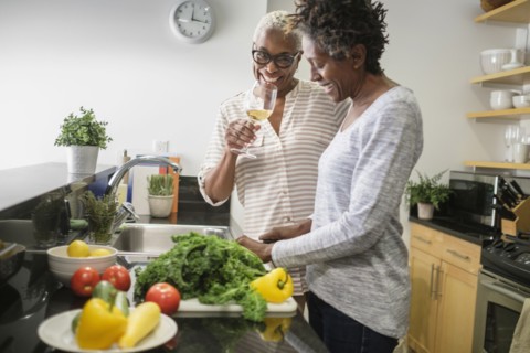 Two women cooking in domestic kitchen.