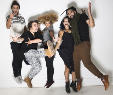 Portrait of group of happy friends against white wall jumping.