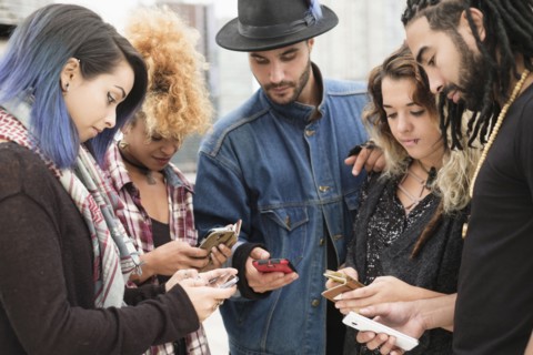 Young people outdoors using smartphones.