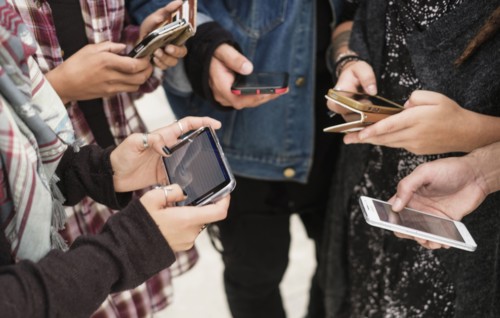 Young people outdoors using smartphones.