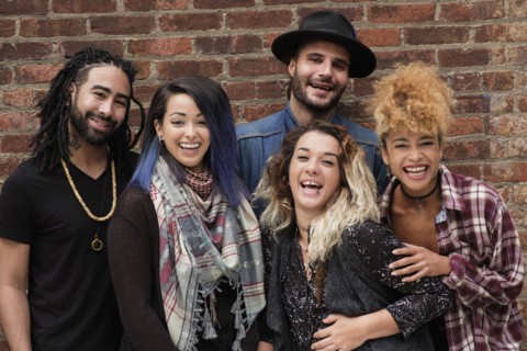 Portrait of happy friends against brick wall.