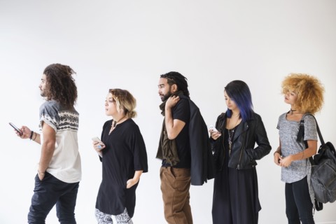 Young people standing in line using smartphones.