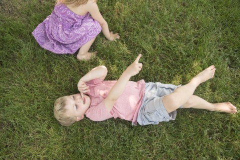 Boy (4-5) and girl (2-3) lying on grass
