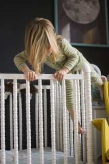 Girl (2-3) climbing on crib