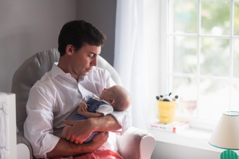 Father holding baby son (0-1 months) by window