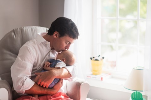 Father kissing baby son (0-1 months) by window